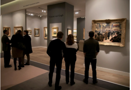 Grupo de pessoas admirando um quadro na feira de arte
