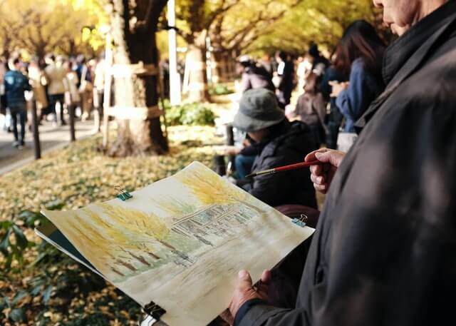 Homem desenhando árvores no papel no parque