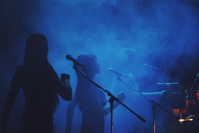 Silhueta de duas mulheres cantando num palco