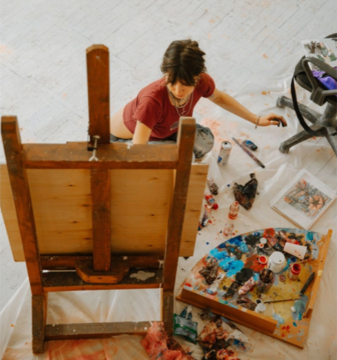 Uma artista no chão pintando uma tela